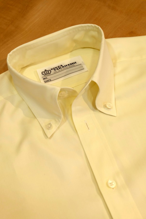 黄色いオックスフォード生地のボタンダウンシャツ。
