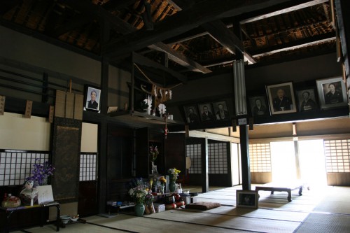 天井がなく、梁と屋根裏がよく見える。中央に見えるのは仏壇。梁に張られた名前の板は、行事などで親族が集まった際に座る位置を示したもの。
