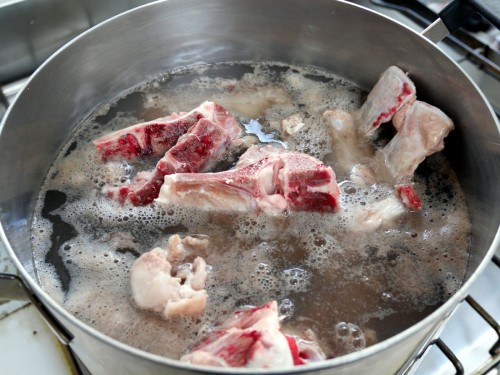 豚の骨（背と腰の骨、尻尾）は熱湯の中で軽く茹で、きれいに洗う（湯洗い）。