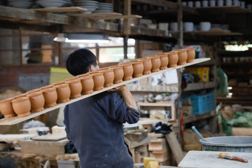 成形した器を運ぶ若き陶工。