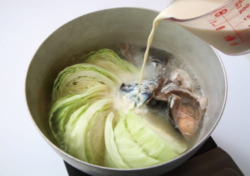 出汁、醤油、塩、鮭、キャベツを鍋に入れて落とし蓋をして強火で沸かす。おろし生姜、豆乳を入れてひと煮立ち。