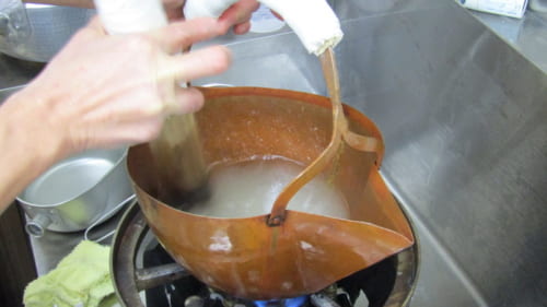 銅製容器で煮溶とかした砂糖をかき混ぜる