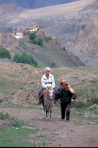 81歳でヒマラヤ登山をしたとき、シェルパに馬の手綱を引かれて。標高4500mの岩陰で、念願のブルーポピー（青い芥子）を見つけた。撮影／岩間幸司